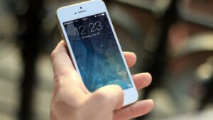 Hand mit iPhone -Symbolbild für Betrug bei Kleinanzeigen