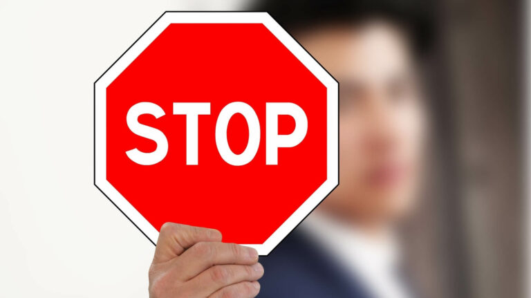 Person hält Stop-Schild - Symbolbild für Beweisverwertungsverbot