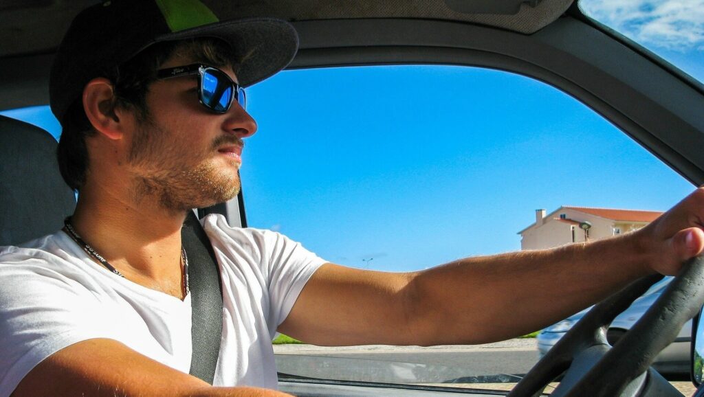 Autofahrer mit Sonnenbrille und Sicherheitsgurt im PKW