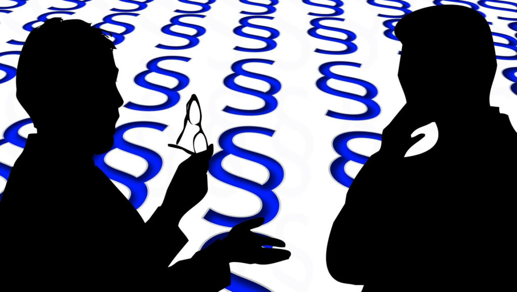 Kündigung wegen Beleidigung von Vorgesetzten; Symbolbild - Silhouette von zwei Personen, die diskutieren, dahinter §§
