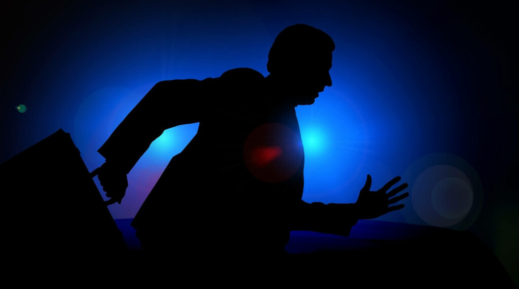 Schattenaufnahme einer Person, die mit einem Koffer weg läuft, blauer Hintergrund mit Scheinwerfern