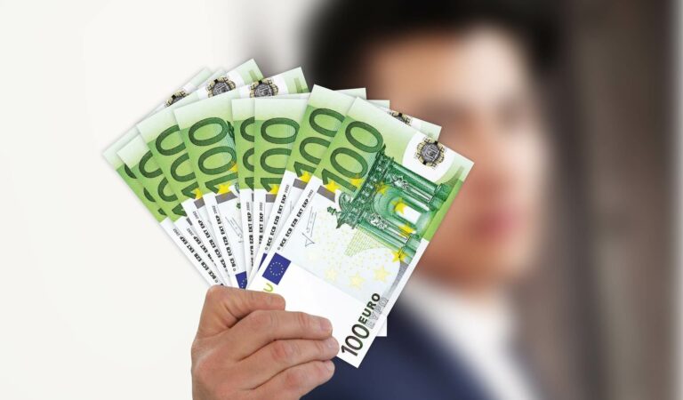 Person mit mehreren gefächerten 100 EUR-Scheinen in der Hand